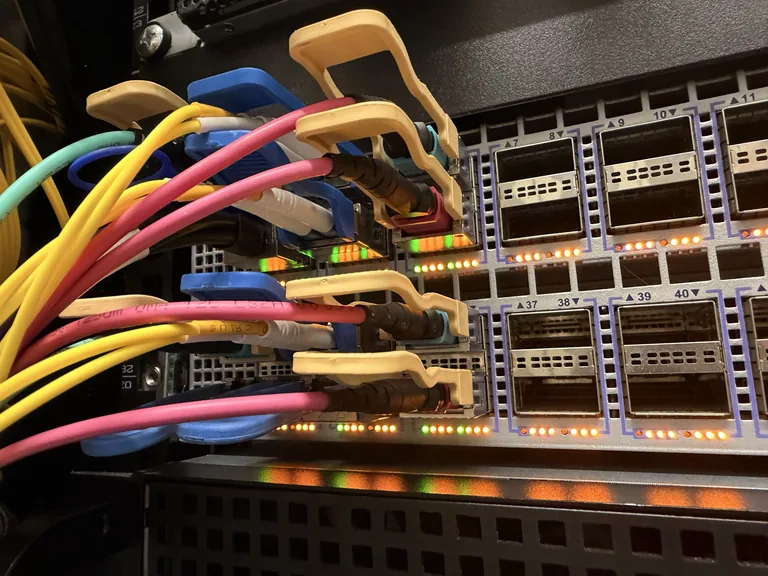 Glasfaserkabel an einem Netzwerk-Switch mit nummerierten Ports und leuchtenden Statusanzeigen