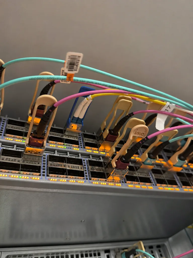 Netzwerk-Switches mit angeschlossenen Glasfaserkabeln und leuchtenden Portanzeigen