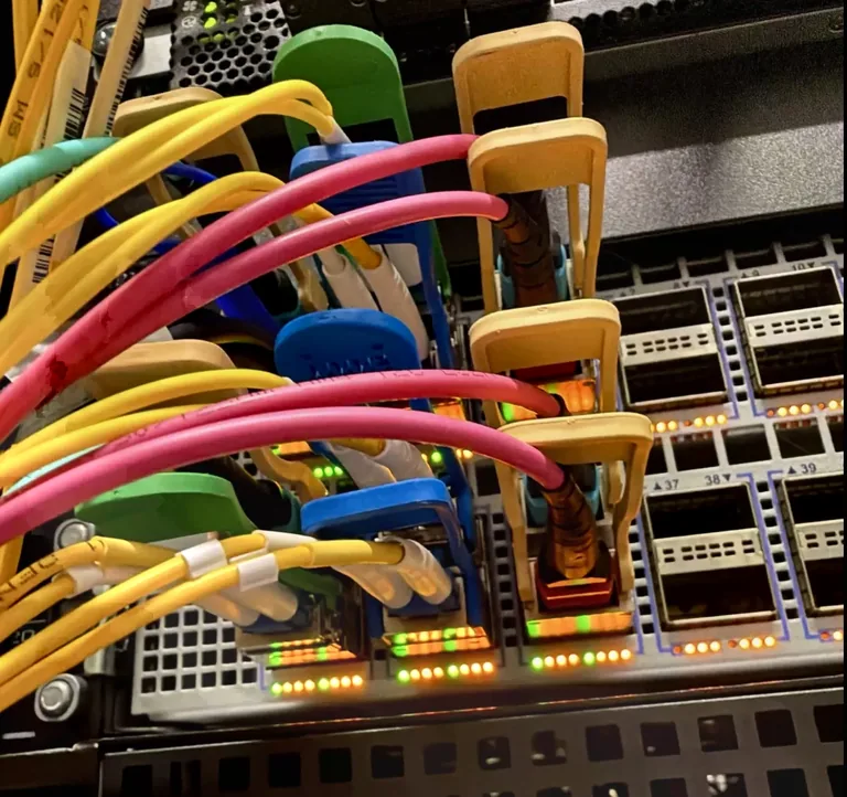Yellow and pink fibre-optic cables in optical switch ports with illuminated status indicators